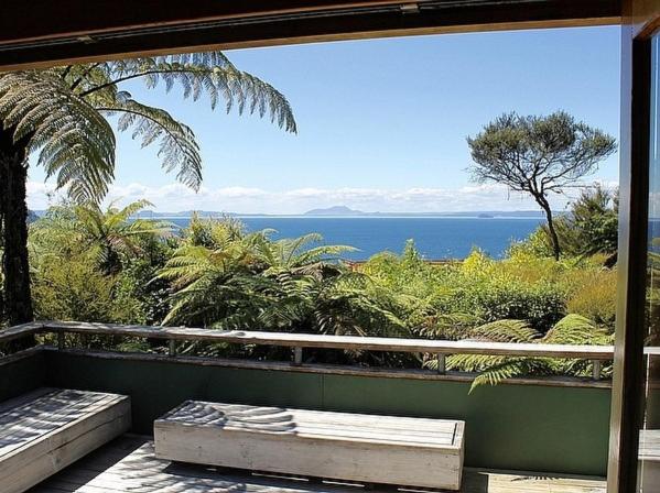 a view of the ocean from a balcony with a bench at Amidst Bush and Birdsong - Pukawa Holiday Home in Kuratau