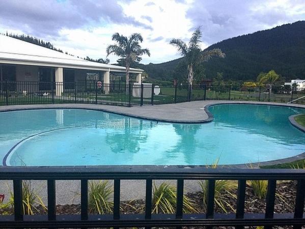 a large blue swimming pool in front of a building at Putt it at Pauanui - Pauanui Holiday Home in Pauanui
