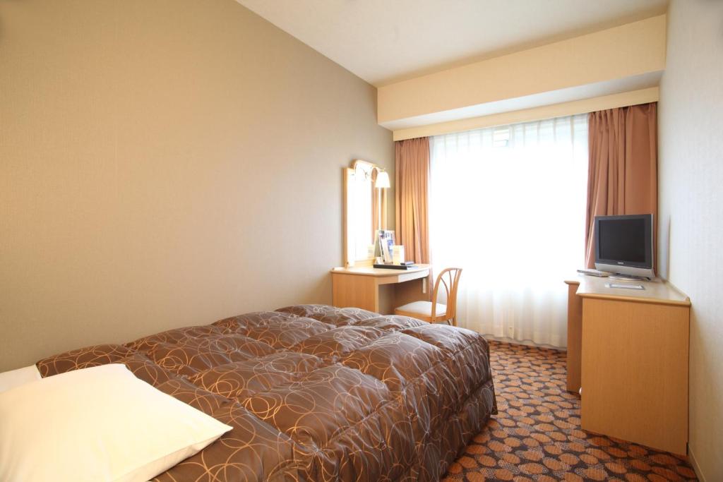 a hotel room with a bed and a television at Hotel Fujita Fukui in Fukui
