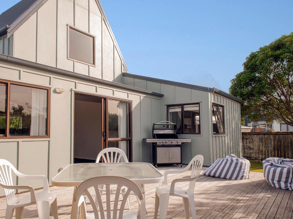 a patio with a table and chairs in front of a trailer at Beach Central - Whangamata Holiday Home in Whangamata