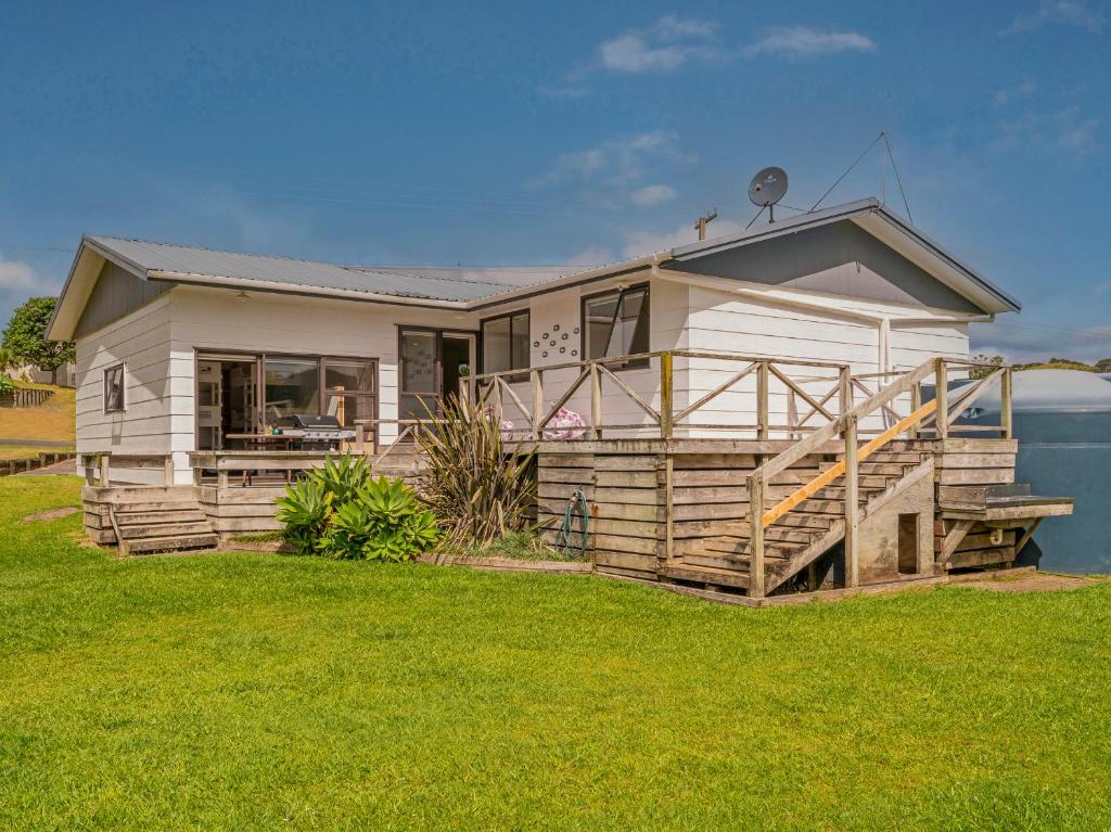 a house with a porch and a large yard at Key to Whangapoua - Whangapoua Holiday Home in Whangapoua