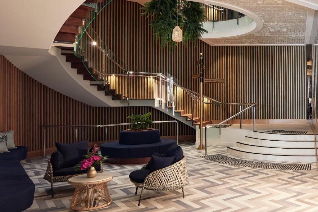 a lobby with a spiral staircase and blue chairs at Crystalbrook Flynn in Cairns