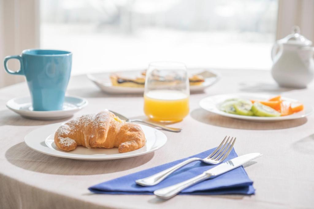 a table with plates of food and a glass of orange juice at Hotel Cavalluccio Marino in Santa Marinella