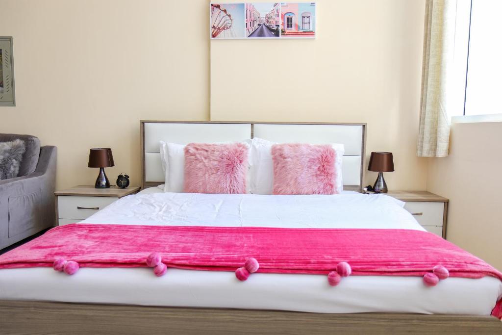 a bedroom with a large bed with pink sheets and pillows at SHH - Furnished Studio Apartment, Silicon Gates 4 in Dubai