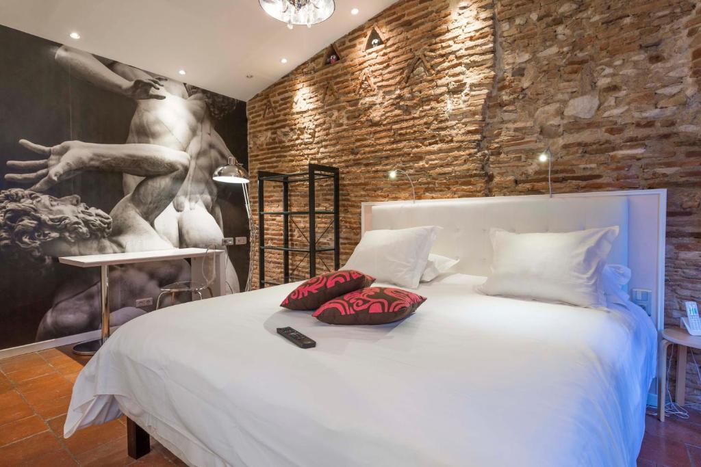 a bedroom with a white bed with red pillows on it at Europe Hôtel in Castres