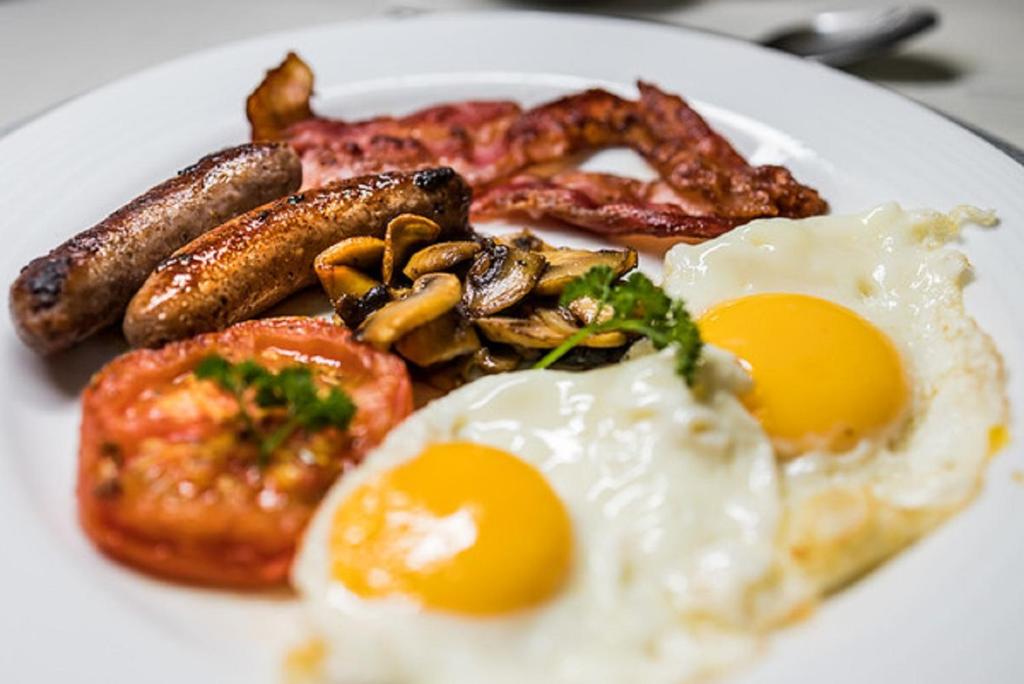 a plate of breakfast food with eggs sausage and mushrooms at Gallo Manor Executive Bed & Breakfast in Johannesburg