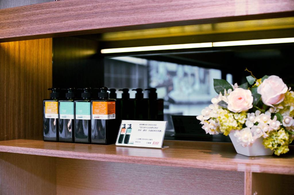 a shelf with several bottles oficating products and a vase of flowers at Talmud Hotel Yizhong in Taichung