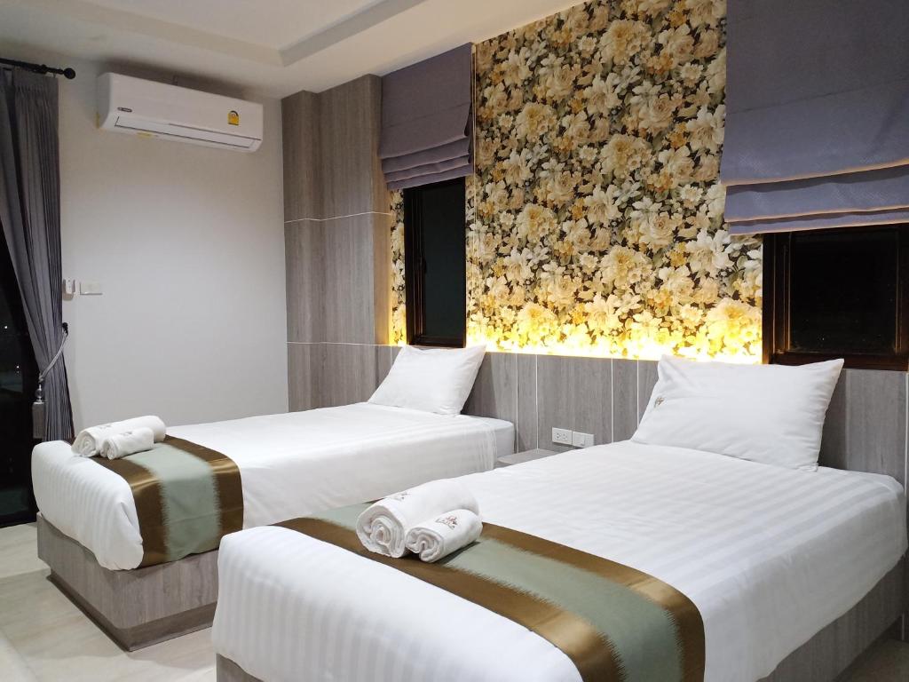 2 camas en una habitación de hotel con flores en la pared en Lailaresidence en Yala