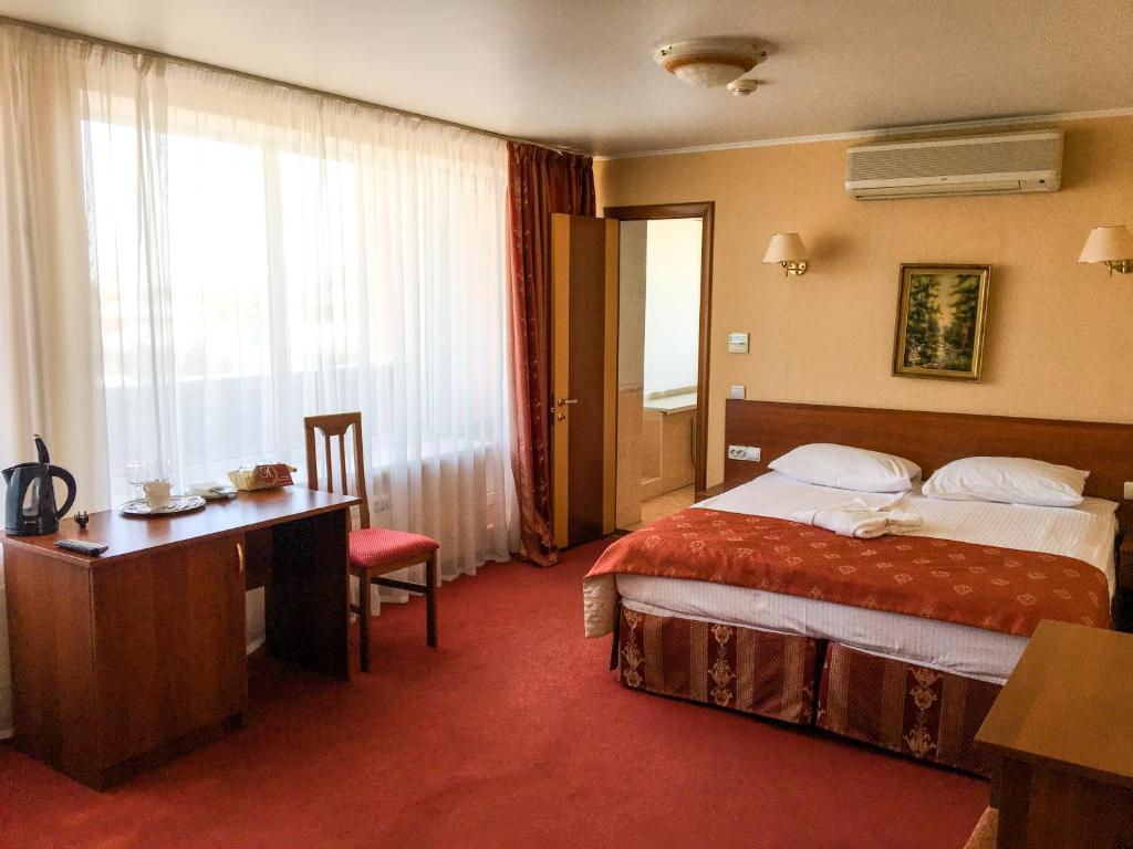 アゾフにあるAMAKS Azov Hotelのベッド、デスク、窓が備わるホテルルームです。