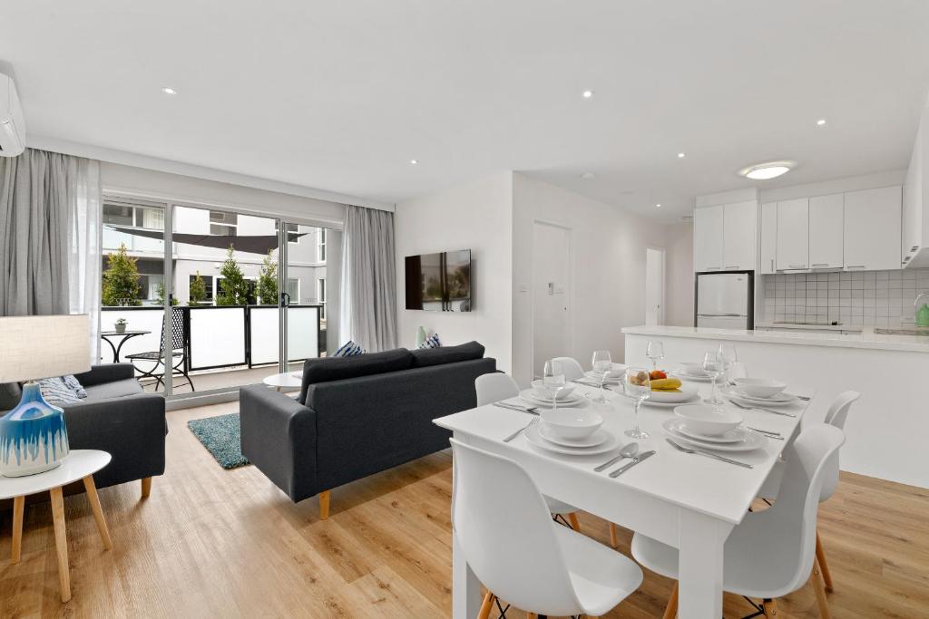 a white kitchen and living room with a white table and chairs at Burwood Serviced Apartments in Burwood
