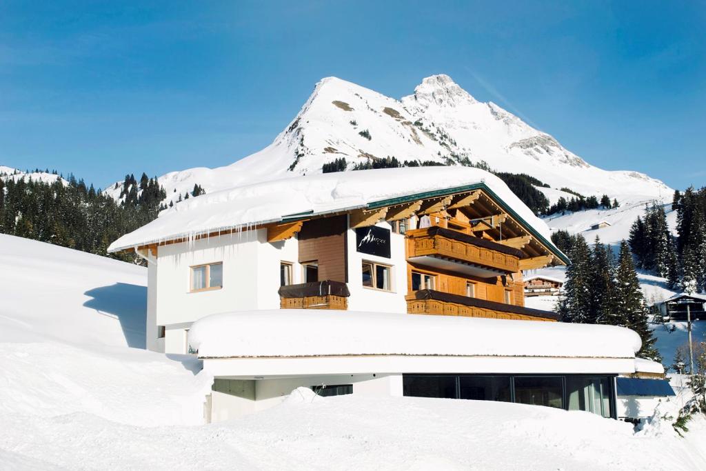 a building covered in snow with a mountain in the background at Birg 1414 in Warth am Arlberg
