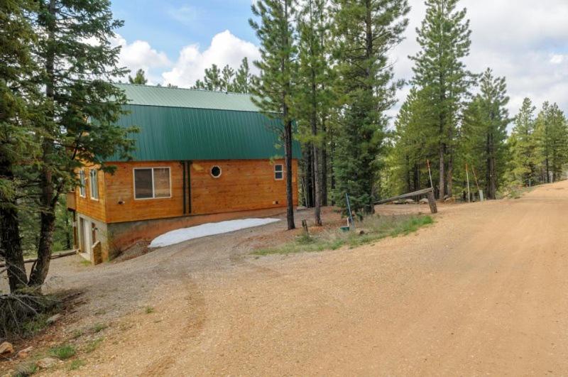 a house with a green roof on a dirt road at S`more Fun Cabin in Duck Creek Village