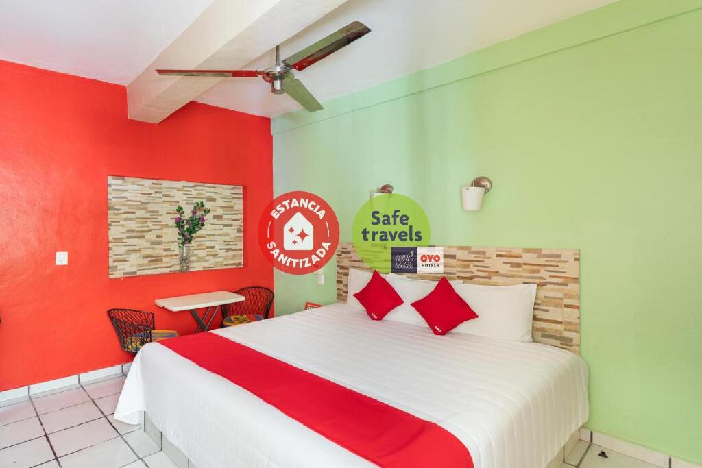 um quarto com uma cama com paredes vermelhas e verdes em Hotel Costa Azul em Chetumal