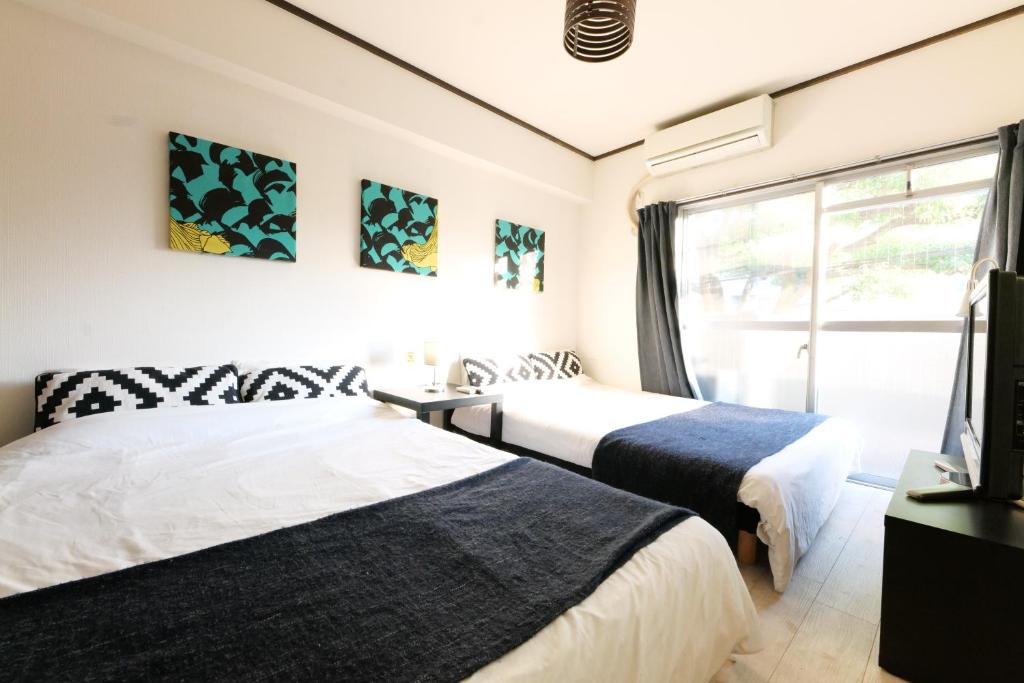 two beds in a room with a window at H2O Stay Kikukawa Woody Sunheim #201 in Tokyo