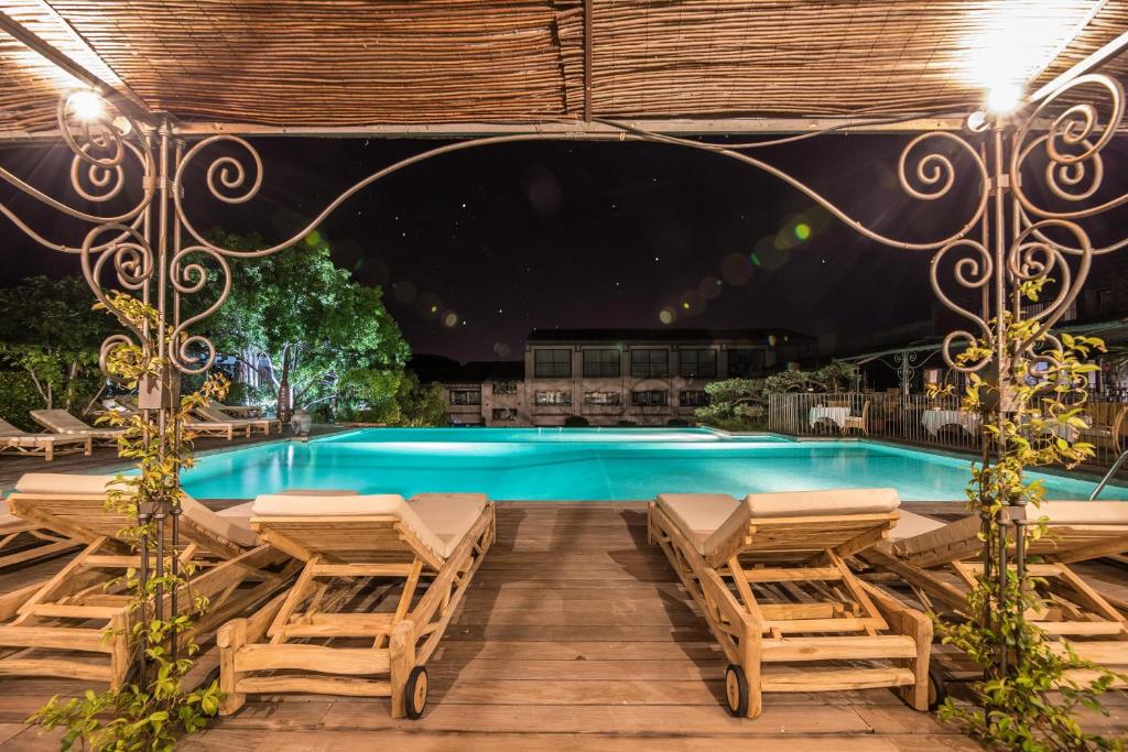 - une piscine avec 2 salons et 2 chaises dans l'établissement Hôtel Le Roi Théodore & Spa, à Porto-Vecchio