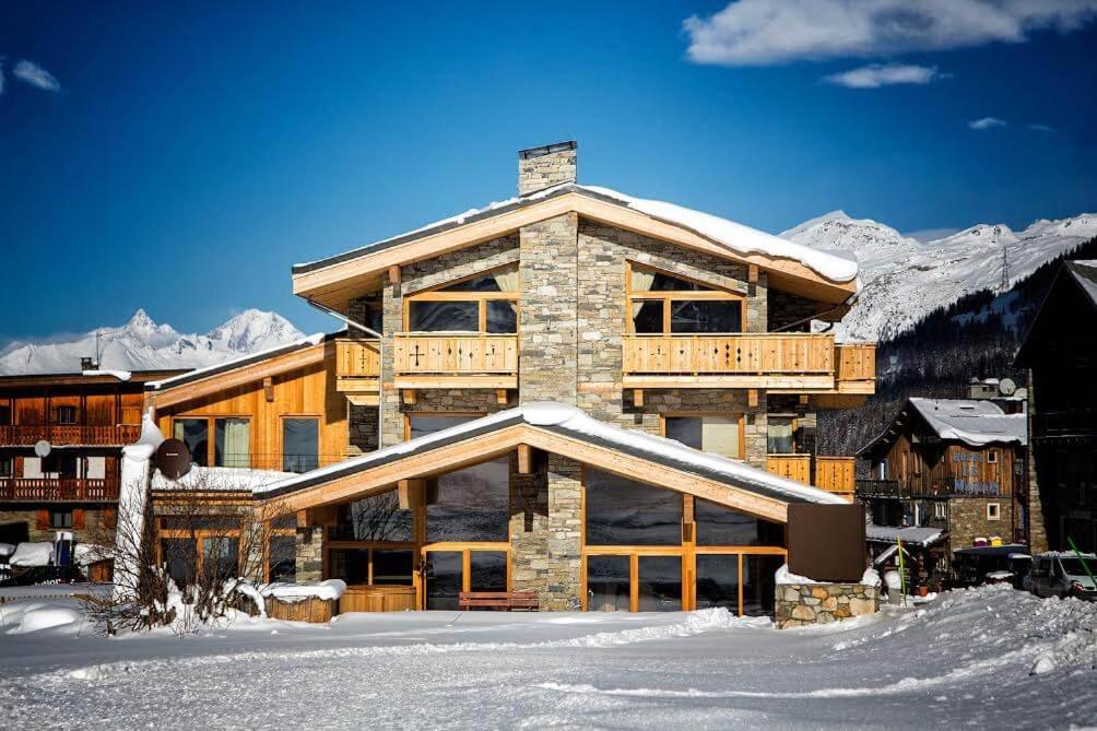 a large wooden building with snow on the ground at Madame Vacances Chalet Alpinium 1 in Les Boisses