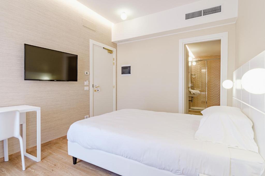 a white bedroom with a bed and a tv on a wall at Hotel Boston in Bari