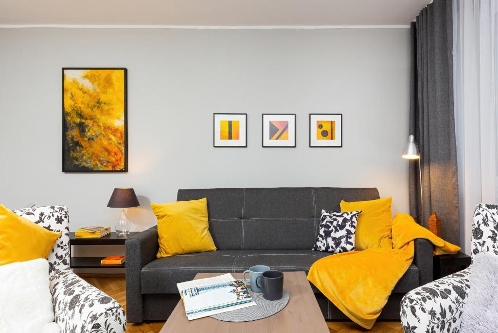 sala de estar con sofá gris y almohadas amarillas en Apartment Warsaw Kredytowa by Renters en Varsovia