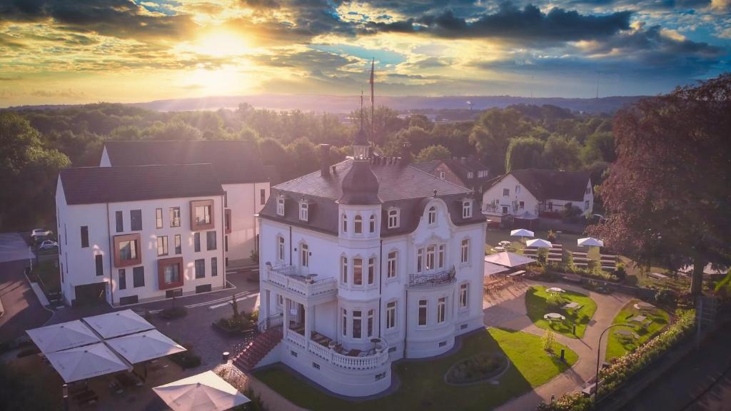 una vista aérea de una casa blanca con la puesta de sol en el fondo en hôtel villa raab en Alsfeld