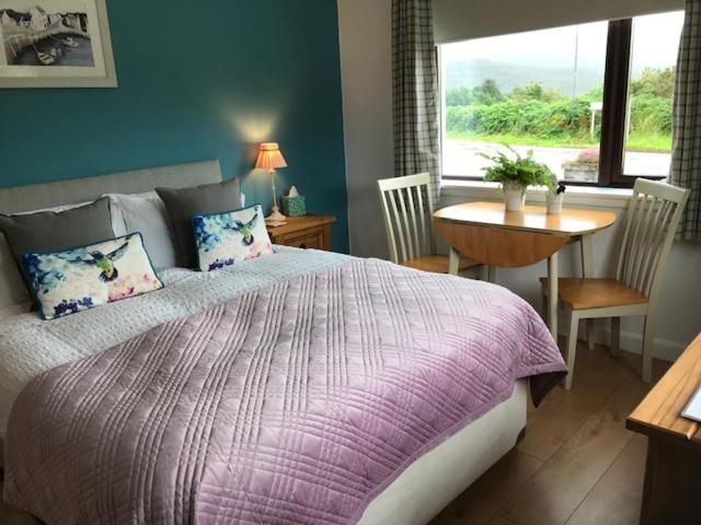 a bedroom with a bed and a table and a window at Millview Ullapool in Ullapool