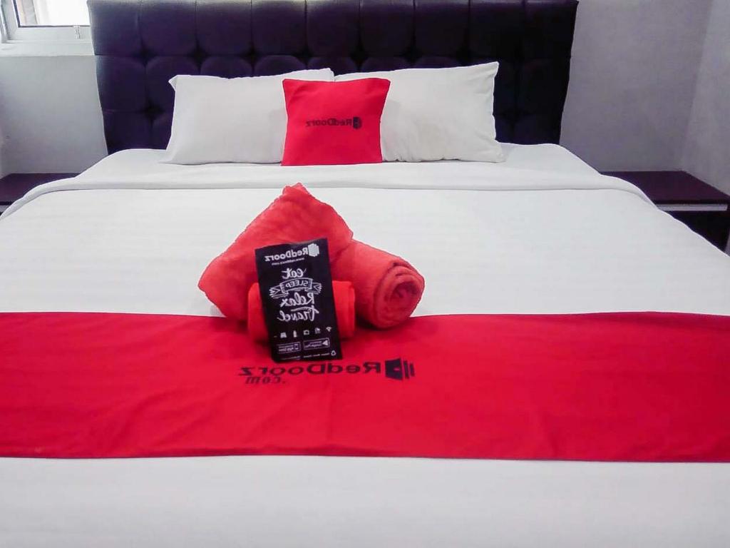a bed with a red blanket and red pillows on it at RedDoorz @ Jalan Pendidikan Mataram in Tanjungkarang