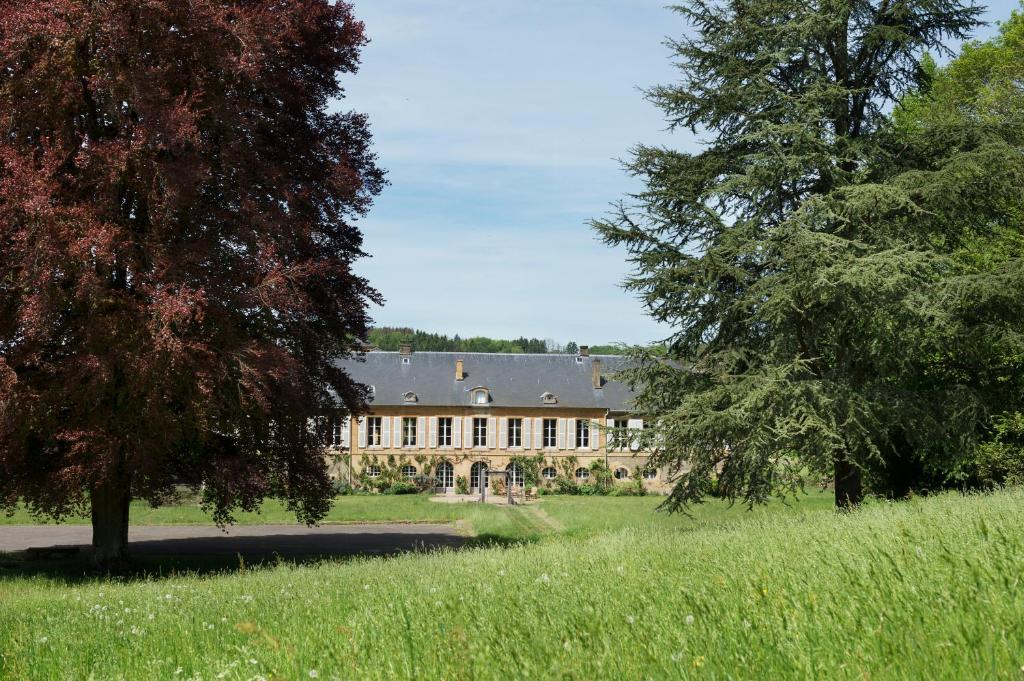 een groot huis in een veld met bomen op de voorgrond bij Château de Martigny 
