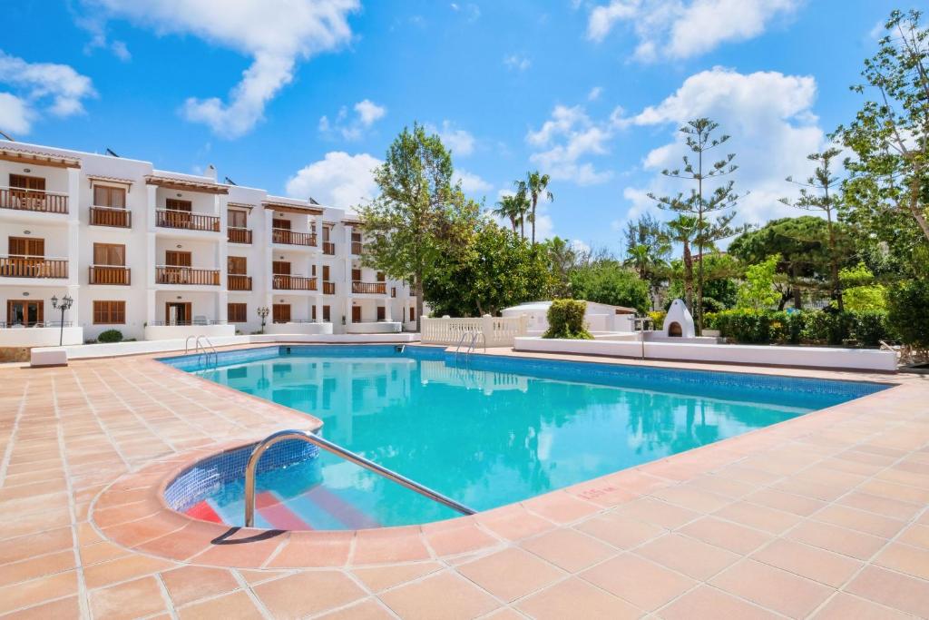 una piscina di fronte a un edificio di azuLine Apartamentos Can Sanso a Santa Eularia des Riu