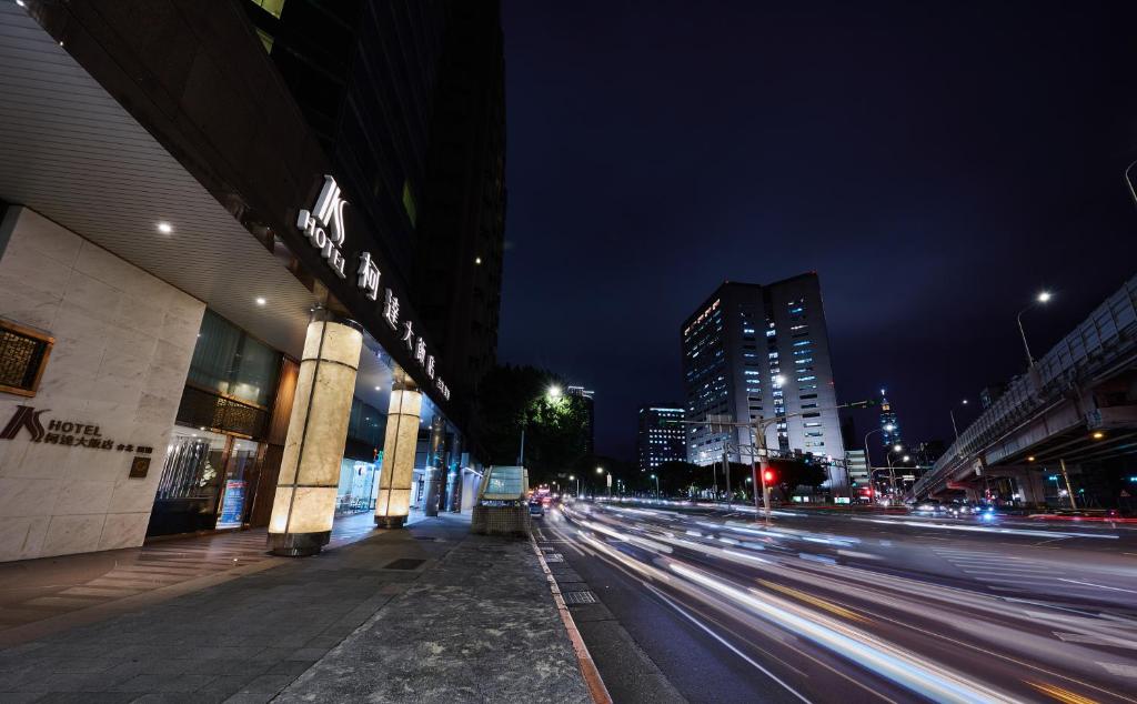 uma rua da cidade à noite com edifícios e carros em K Hotel Taipei Dunnan em Taipei