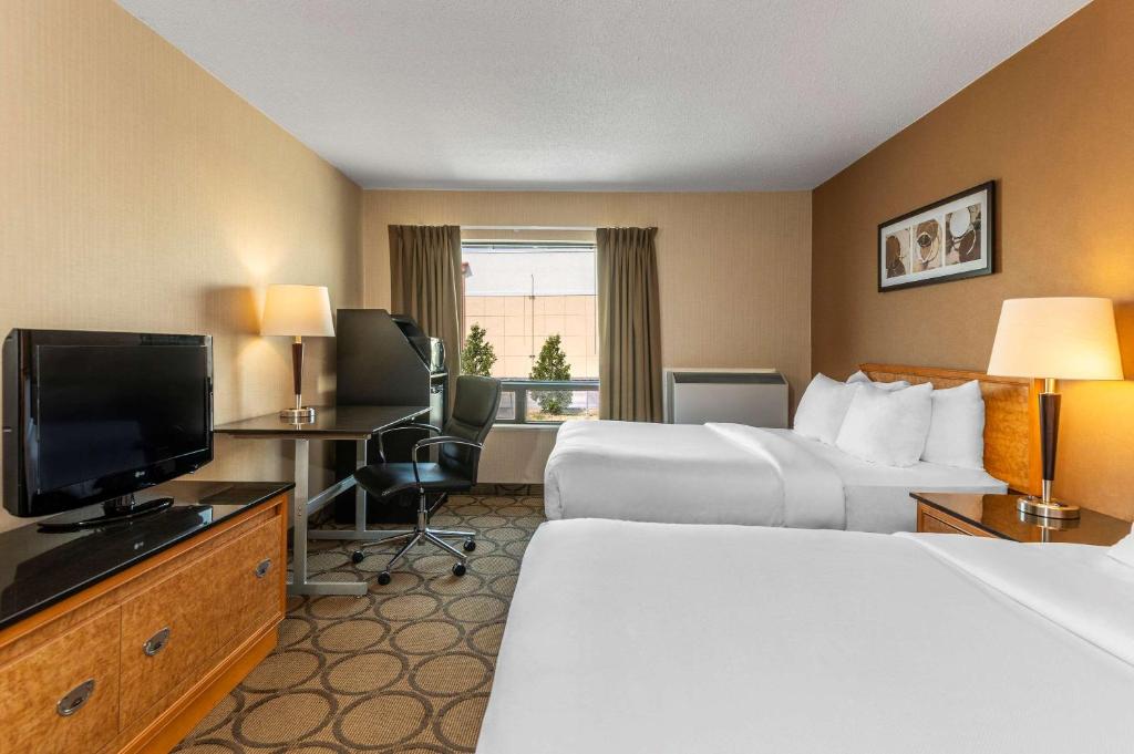 a hotel room with two beds and a flat screen tv at Comfort Inn in Saguenay