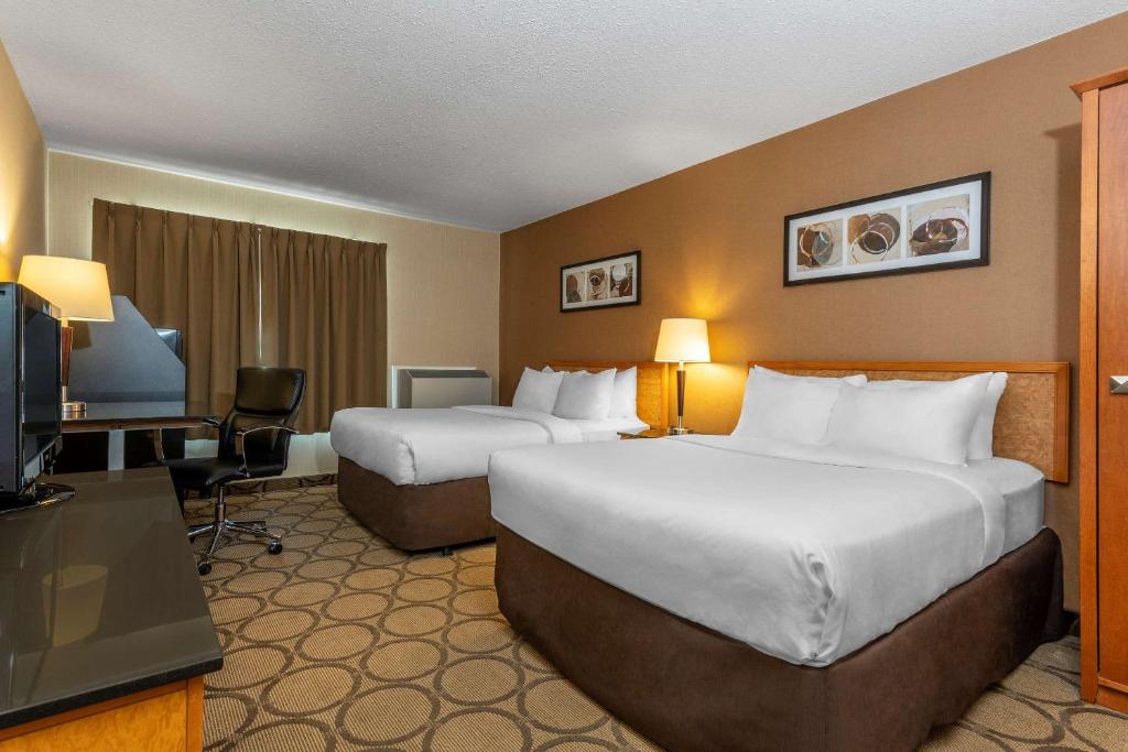 a hotel room with two beds and a flat screen tv at Comfort Inn in Saguenay