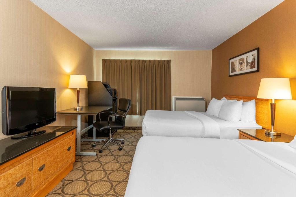 a hotel room with two beds and a flat screen tv at Comfort Inn in Saguenay