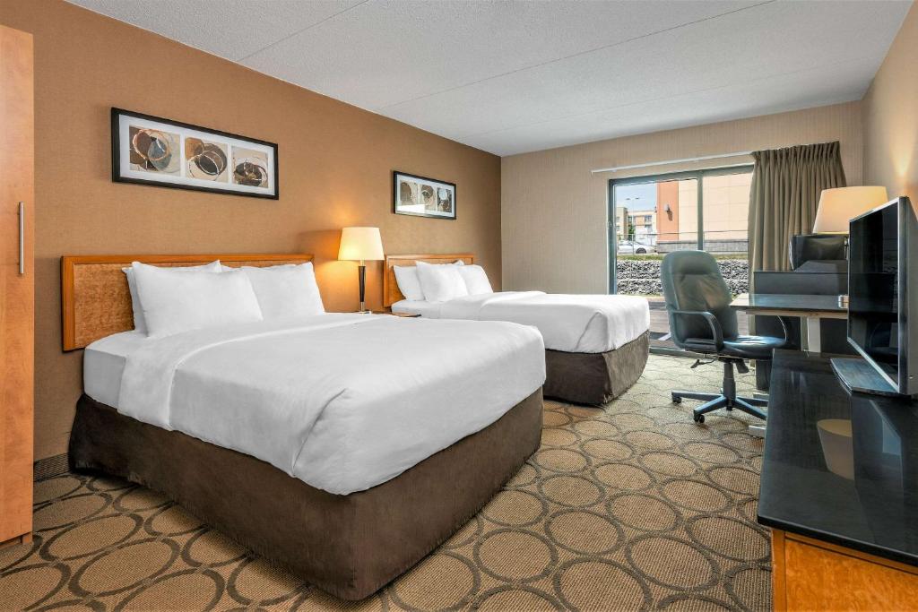 Cette chambre comprend deux lits et une télévision. dans l'établissement Comfort Inn Winnipeg South, à Winnipeg