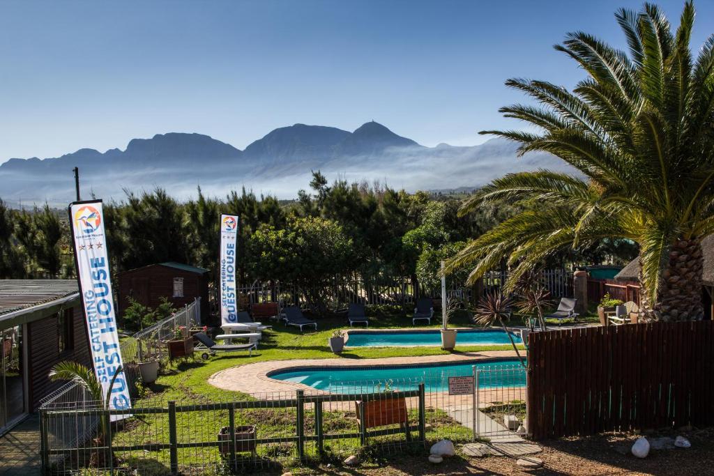 a resort with a swimming pool with mountains in the background at Kingfisher Hollow in Gordonʼs Bay