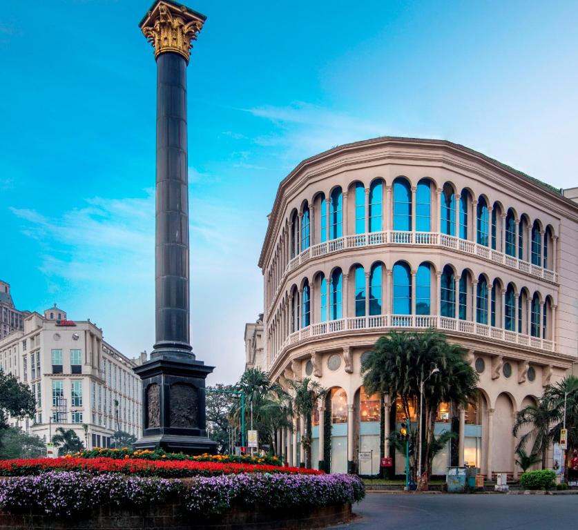 a pole in front of a building with a clock tower at Rodas An Ecotel Hotel in Mumbai