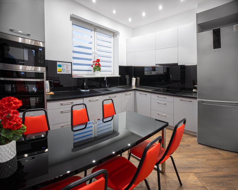 kuchnia ze stołem i czerwonymi krzesłami w obiekcie Apartament Pod Czantorią - Nowoczesny apartament z widokiem na Czantorię w Ustroniu