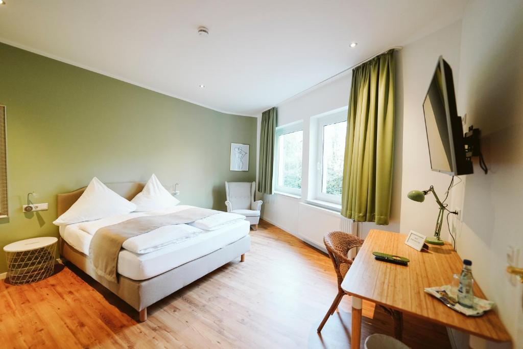 a bedroom with a bed and a desk and a television at Hotel Grüner Baum in Hamm