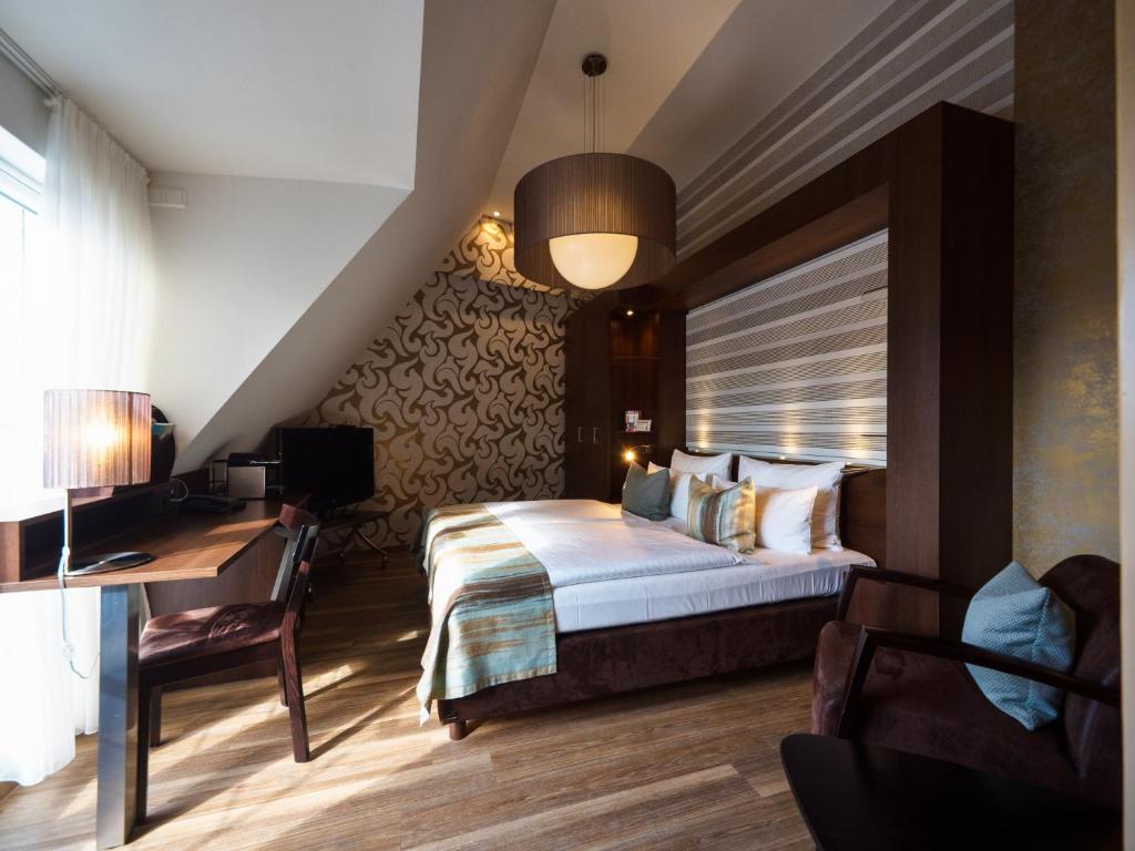 a hotel room with a bed and a desk and a bed and a room at Hotel Leidinger - ehemalige Domicil und Domaine Leidinger in Saarbrücken