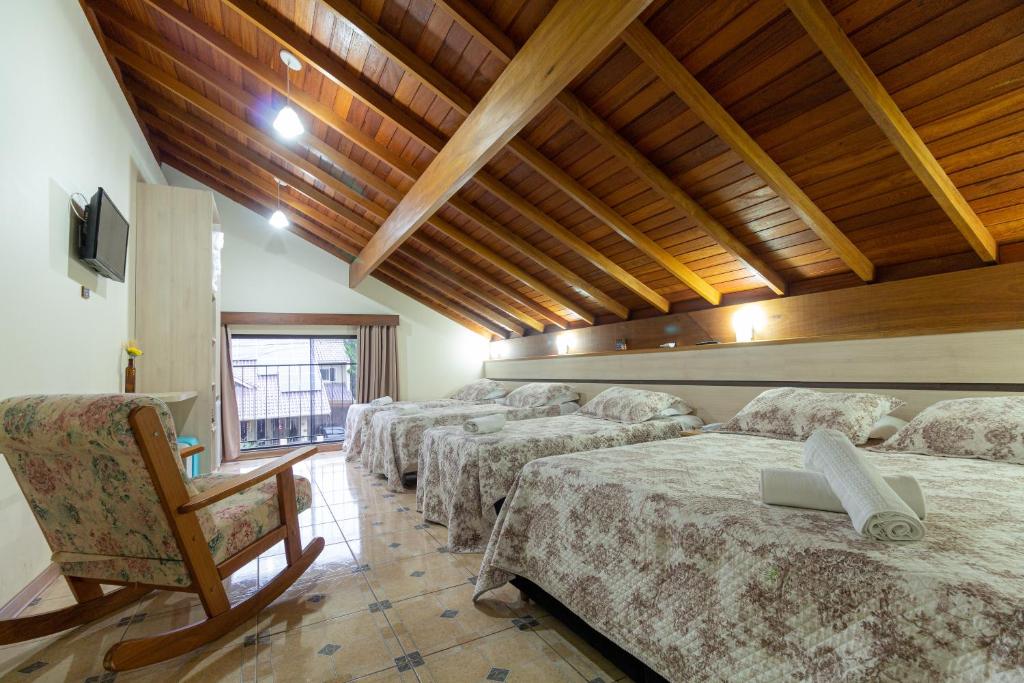 a row of beds in a room with wooden ceilings at Hotel Park Haus in Nova Petrópolis