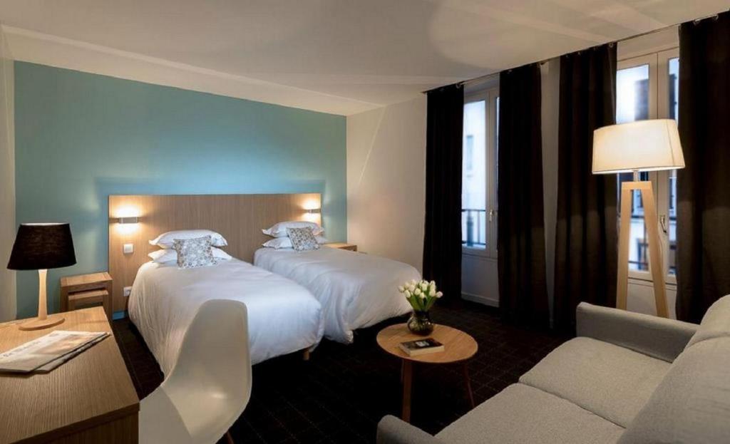 a hotel room with two beds and a couch at Hotel Mirabeau Eiffel in Paris