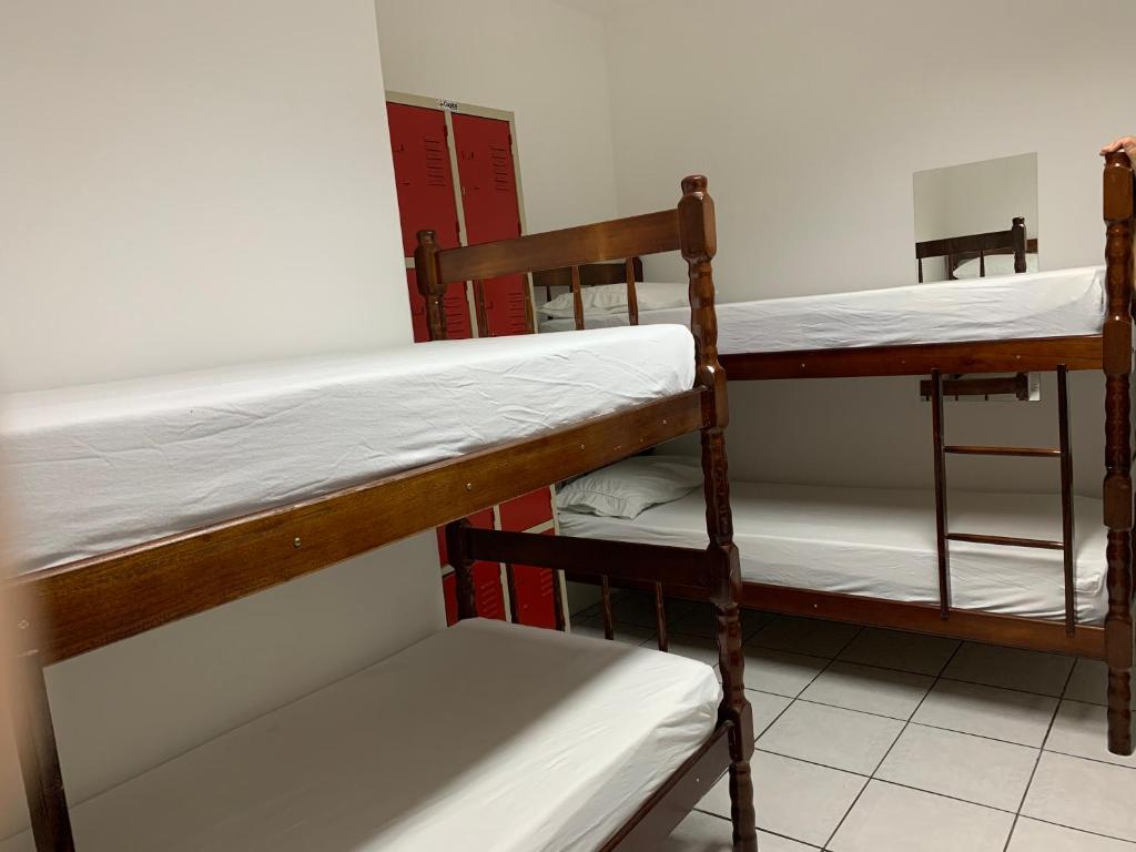 a dorm room with two bunk beds and a chair at Positive Hostel in Balneário Camboriú