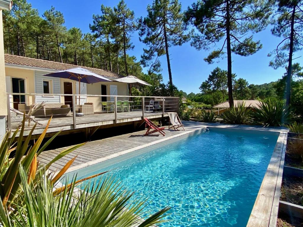 a swimming pool with a deck and a house at Villa les Mimosas with pool and fantastic views in Lacanau