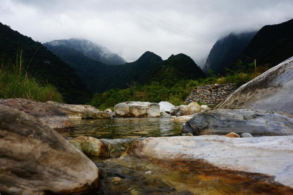 景美村的住宿－花蓮三棧頌月民宿，一条以岩石和山脉为背景的河流