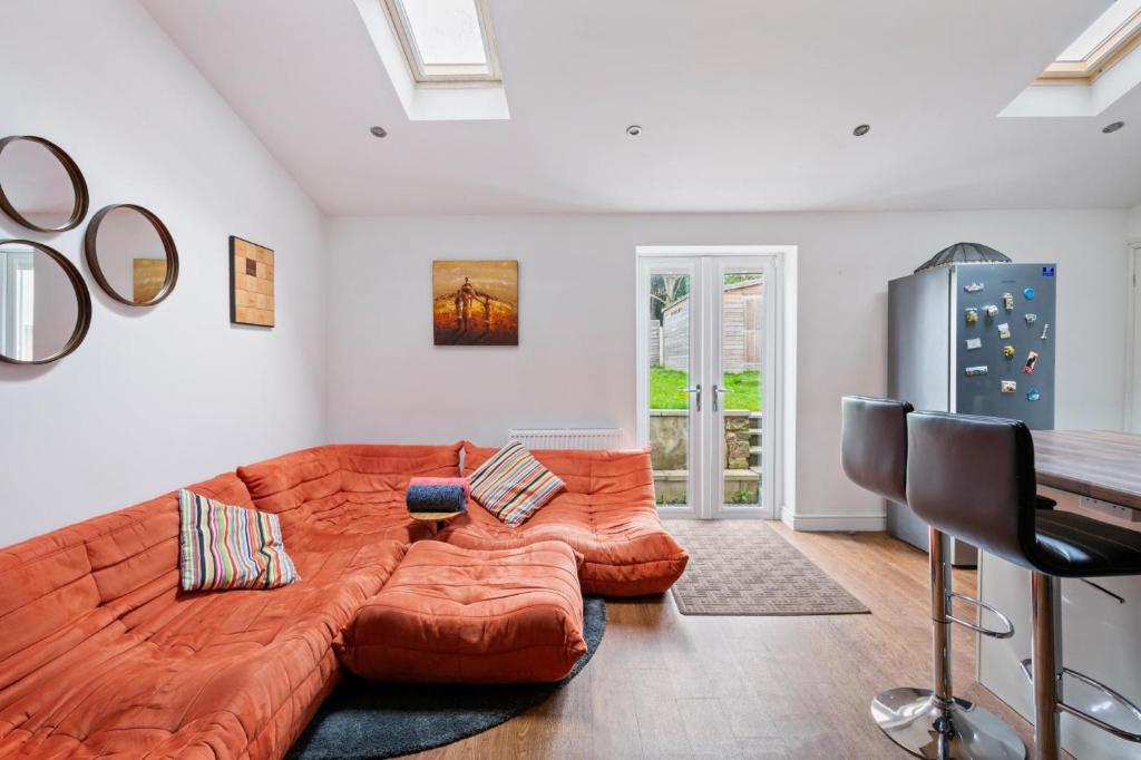 a large orange couch in a living room with a piano at NEW Bright & Stylish 4BD Home City Centre of Leeds in Leeds