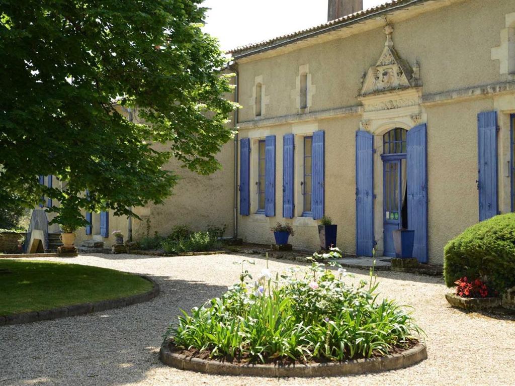 un bâtiment avec des portes bleues et des fleurs devant lui dans l'établissement Chambres d'Hôtes La Sauvageonne, à Saint-Palais