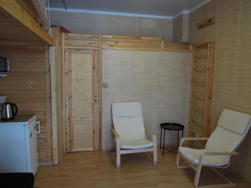 オムスクにあるHostel Omskのドア付きのお部屋に白い椅子2脚