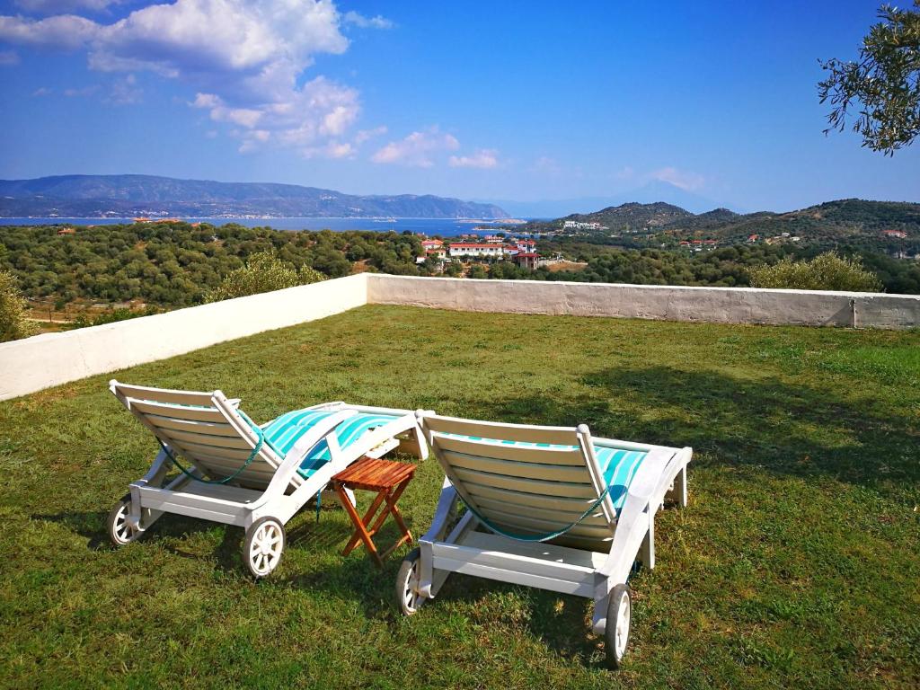 two rocking chairs sitting on top of a field of grass at Olive Bay Hilltop Apartments Ammouliani in Ammouliani
