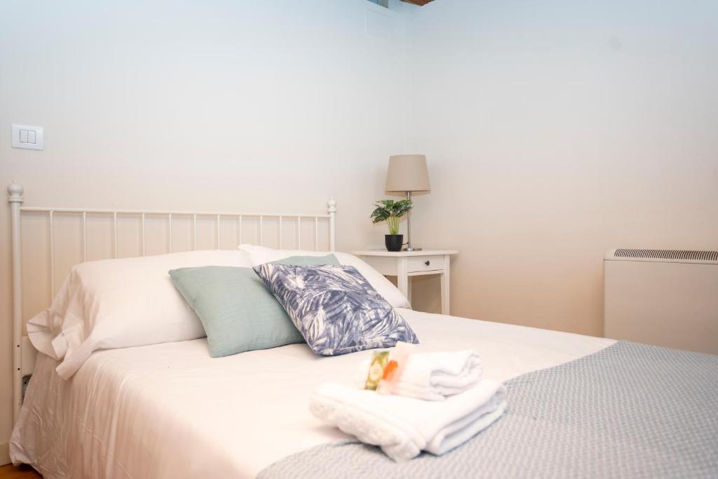 Un dormitorio con una cama blanca con toallas. en Turistiqa - Ferrol - Triplex Centro, en Ferrol