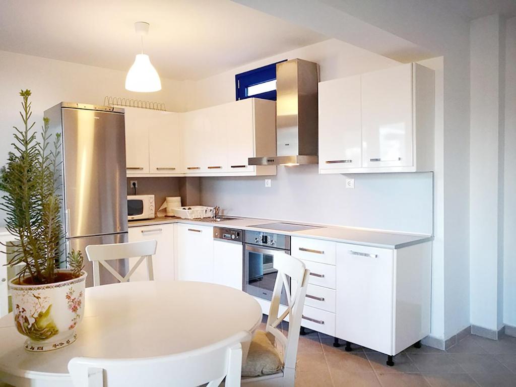 a kitchen with white cabinets and a table with a potted plant at Olive Bay Hilltop Apartments Ammouliani in Ammouliani