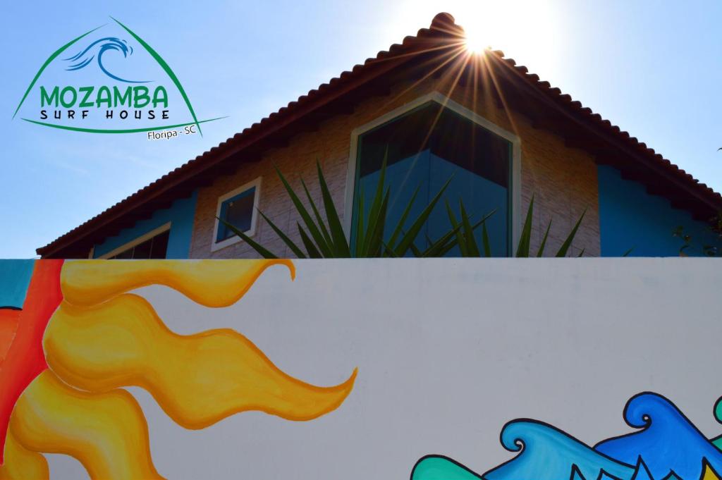 una casa con el sol brillando en el techo en Mozamba Surf House, en Florianópolis