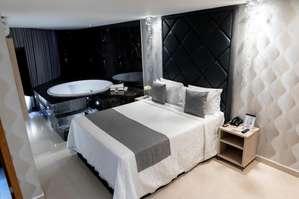 巴西利亞的住宿－Cancún Hotel by H Hotéis - Airport，一间卧室设有一张大床和一个浴缸
